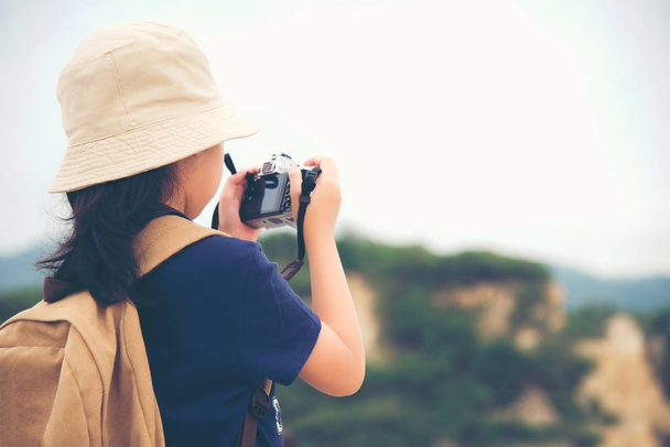 Mutlu beyaz çocuk Asyalı kız sırt çantası gülümseyen ve kamera için tutarak fotoğraf çek dağda alıyor. Seyahat kavramı. - Fotoğraf, Görsel