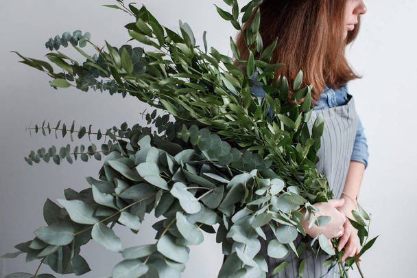 Florist makes a bouquet. Process of work. woman holding a bouquet of eucalyptus in hands - Photo, Image