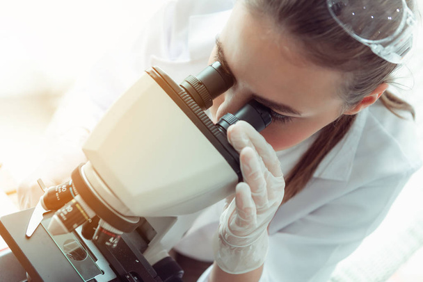 Portret van een jonge wetenschapper onderzoek met behulp van de Microscoop in een laboratorium, biotechnologie, Science, chemie. - Foto, afbeelding