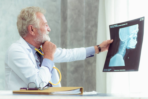 Πορτρέτο της ανδρικής ανώτερος γιατρός εξετάζει την ταινία X-Ray εξέταση δωμάτιο., υγειονομικής περίθαλψης και επαγγελματική έννοια. - Φωτογραφία, εικόνα