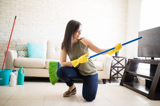 Young woman playing around with broom guitar - Foto, imagen