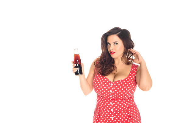 attractive plus size woman with bottle of soda looking at camera isolated on white - Photo, Image