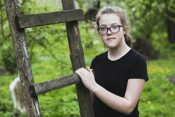 portrait of teenage girl with wooden ladder outdoors by summer - Foto, Bild