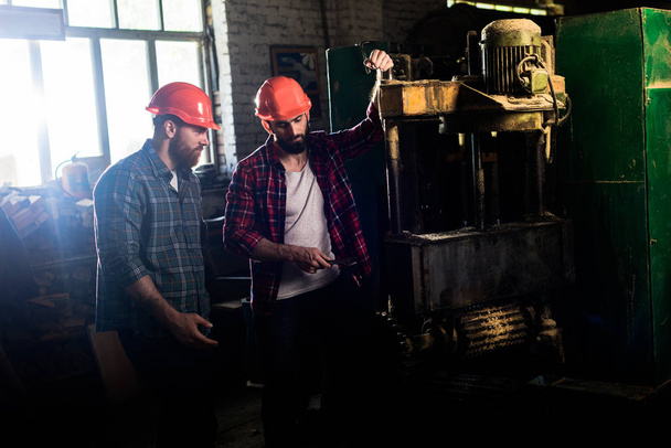 ξυλουργούς στα Κράνη προστασίας χρησιμοποιώντας μηχανή εργαλείο στο πριονιστήριο  - Φωτογραφία, εικόνα