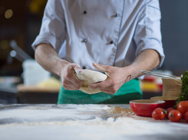 chef hands preparing dough for pizza on table sprinkled with flour closeup - Fotó, kép