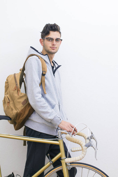 молодий з рюкзаком і велосипедом у білій стіні
 - Фото, зображення