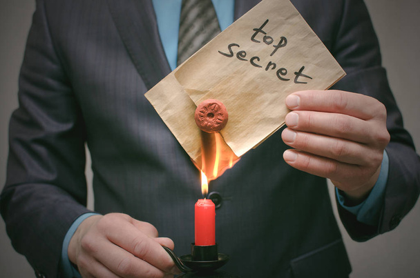 Top secret message concept. A business man burning secret documents on fire. Destruction of indications. Destruction of evidence. Person cover his tracks. - 写真・画像