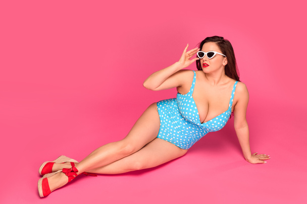 full length view of sexy size plus woman in swimsuit and sunglasses resting isolated on pink - Foto, Imagen