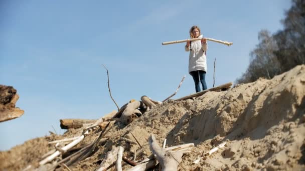 Krásná mladá žena po břehu řeky a sbírání suchých větví - Záběry, video