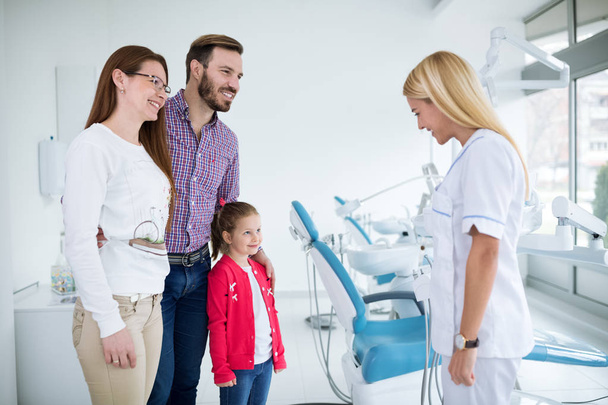 Young female dentist encourages family in dental office - Foto, Imagen