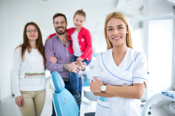 Family with a smiling young dentist in a dental office - Foto, Imagen
