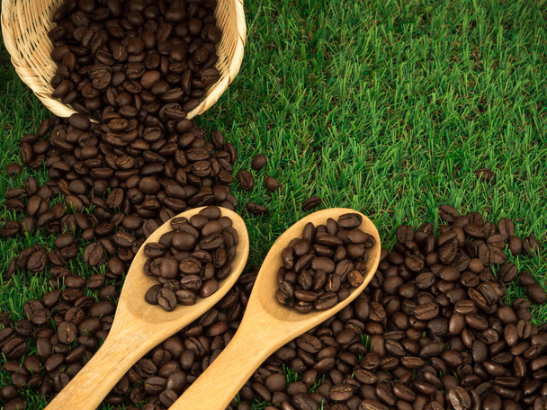 Cup of coffee and coffee beans on wooden spoon and and biscuit on grass green background - Photo, Image
