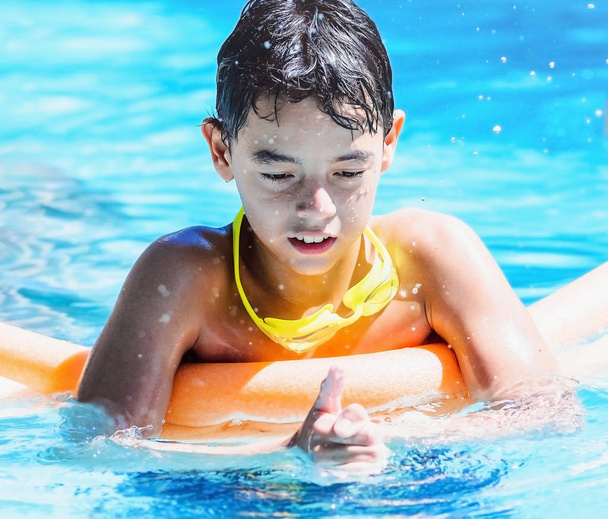 Garçon jouer sur la piscine en appuyant sur l'eau avec les mains et éclaboussures d'eau autour
. - Photo, image
