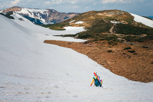 Caminhante feminina em um terno de unicórnio se divertindo na neve nas montanhas dos Cárpatos em um dia de primavera. Conceito de viagem Wanderlust
. - Foto, Imagem