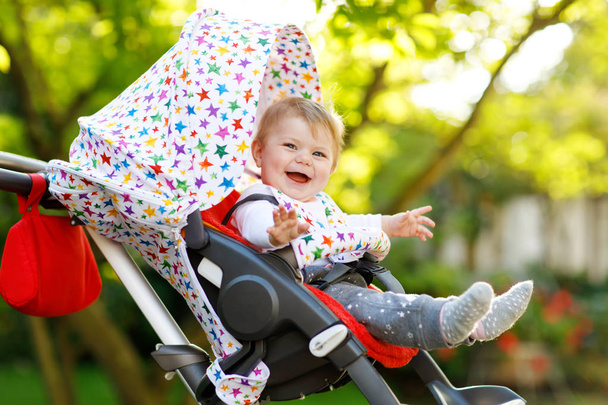 Bonito pequena menina bonita de 6 meses sentada no carrinho de bebê ou carrinho e esperando a mãe
 - Foto, Imagem
