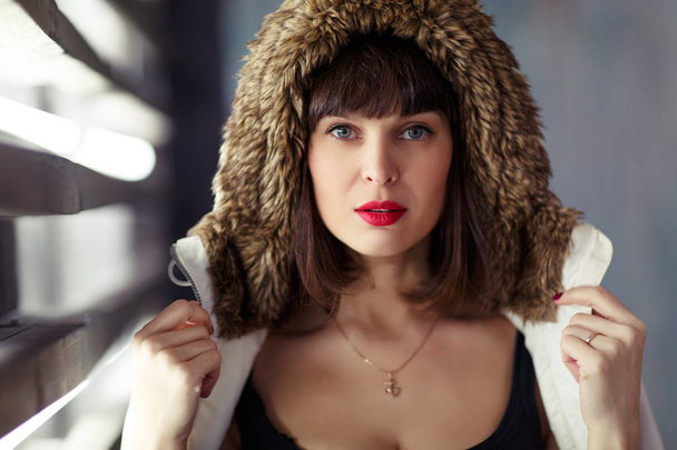 Photo of young brunette in jacket with fur hood - 写真・画像