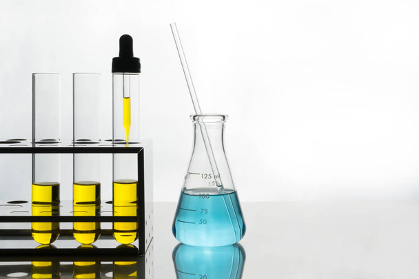 лабораторная сцена, желтая жидкость в пробирках и капельнице, голубая жидкость во фляжке
. - Фото, изображение