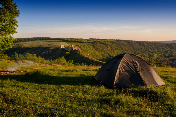 Gündoğumu, yeşil çimenlerin üzerinde turist çadır. Eski bir kalenin arka planı - Fotoğraf, Görsel