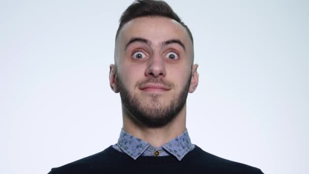 Closeup portrait of young handsome man face expressing astonishment and admiration in studio on white background - Filmati, video