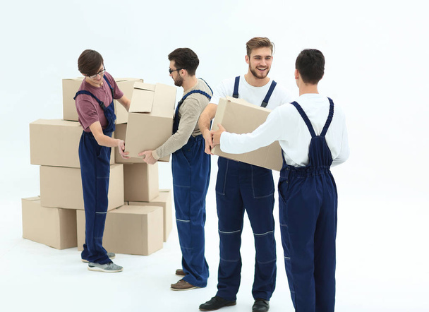 Movers lifting stack of cardboard moving boxes isolated on white - Фото, изображение