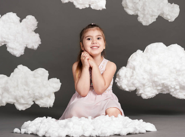 lány játék a felhőkkel, lövés a stúdióban egy szürke háttér - Fotó, kép