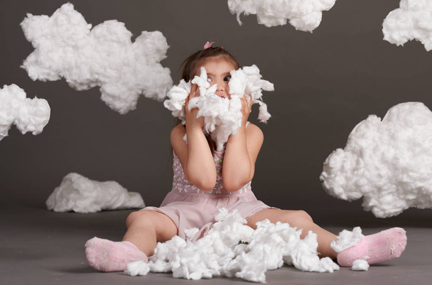 girl playing with clouds, shot in the studio on a gray background - Photo, Image