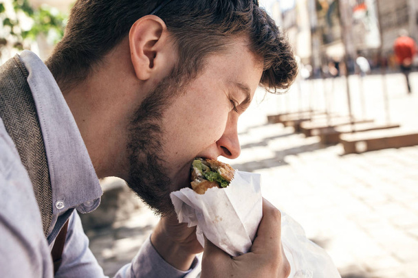 όμορφος άντρας δάγκωμα και δοκιμάζοντας νόστιμα σάντουιτς κρουασάν - Φωτογραφία, εικόνα