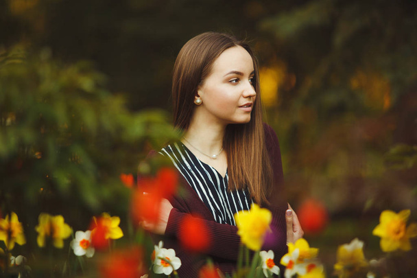 beautiful girl sits at the planted flowers. - Foto, Bild