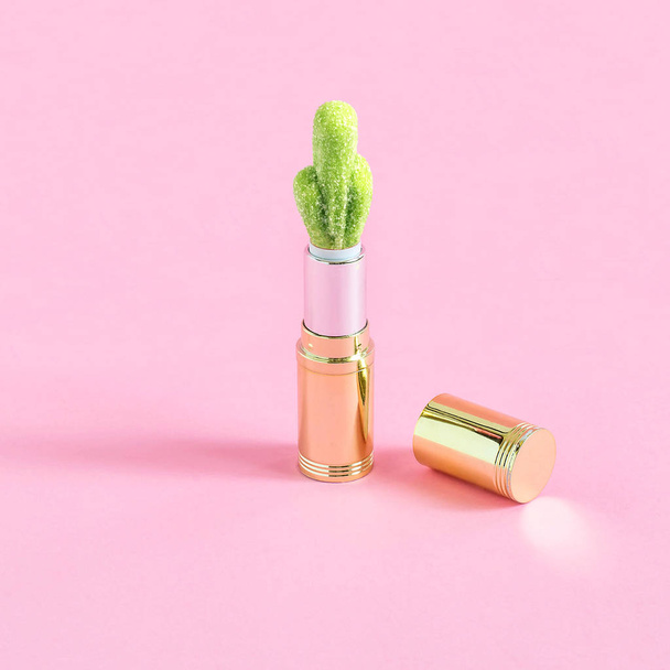 Buis van lippenstift en snoep in de vorm van de cactus op pastel roze achtergrond. Minimalistische stijl. Creatief idee van kleur en vorm. Fantasieën over thema van voedsel en misbruik van sweet - Foto, afbeelding