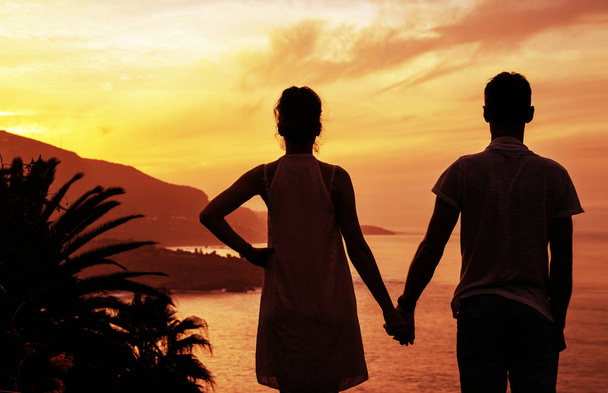 陽気なカップルが美しい、熱帯の夕日を見て - 写真・画像