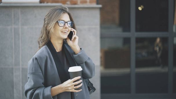 Businesswoman in glasses with coffee outside, side - Foto, imagen
