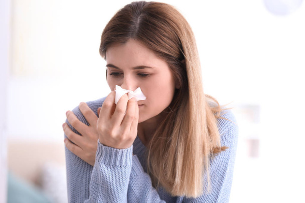 Sad woman with tissue suffering from cold on blurred background - Foto, afbeelding