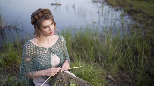 Tejido de punto a mano de mujer haciendo tela de lana. chica está sentada en el lago
 - Metraje, vídeo