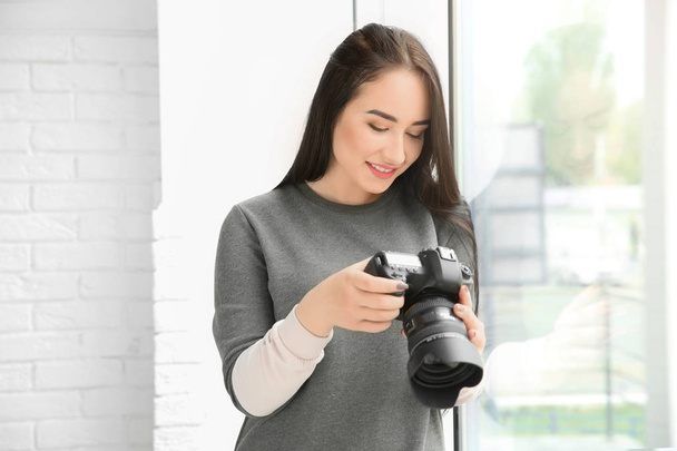 Young female photographer with professional camera indoors - Φωτογραφία, εικόνα