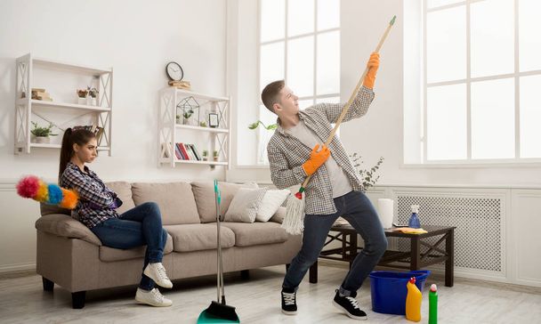 Νεαρό ζευγάρι καθαρισμού σπίτι, παίζοντας με σφουγγαρίστρα - Φωτογραφία, εικόνα