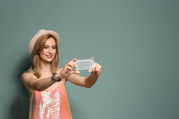 Attractive young woman taking selfie on color background - Foto, afbeelding