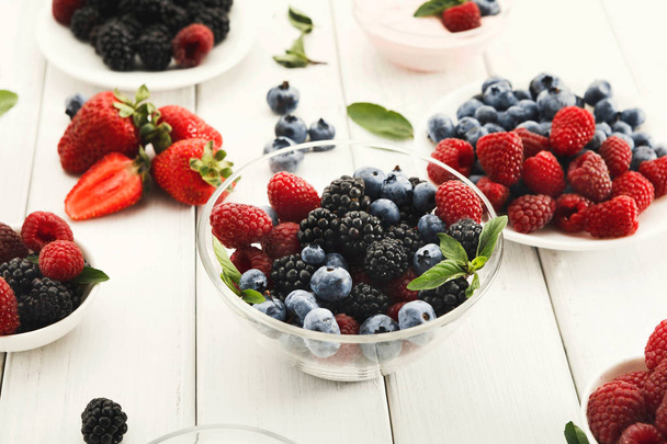 Mixed berries in glass bowls on white wooden table - Photo, Image