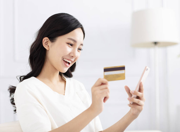 onnellinen nainen ostoksia luottokortilla ja älypuhelimella
 - Valokuva, kuva