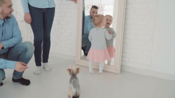 Beautiful little girl stay near the mirror with her family and dog. Slow Motion. Baby milestone, toddler, 1 year old. Happy childhood - Materiał filmowy, wideo
