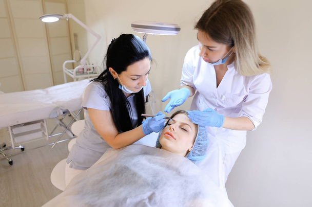 Dama europea visitando dermatólogo profesional y cosmetólogo para maquillaje permanente
. - Foto, imagen