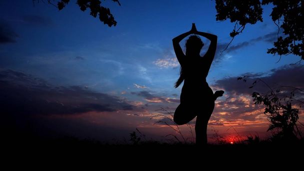 Shadow naisten siluetti auringonlaskun taustalla, nainen tekee joogaa ennen nukkumaanmenoa
. - Valokuva, kuva