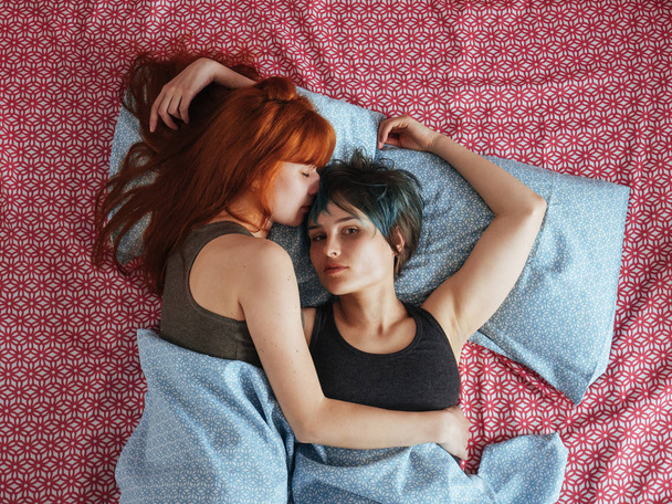 Women lying on the bed, young lesbians kisses and hugs - 写真・画像