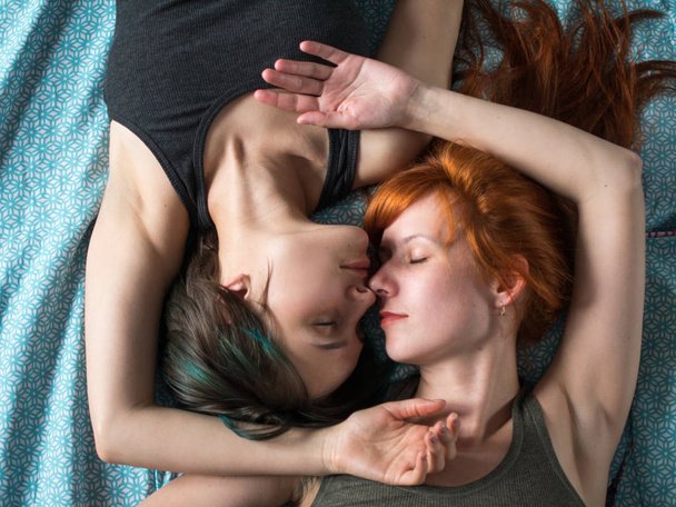 Two girlfriends lay on the bed, top view. - Fotoğraf, Görsel