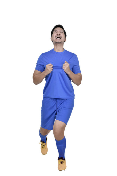 Happy asian football player man celebrate after scoring a goal isolated over white background - 写真・画像