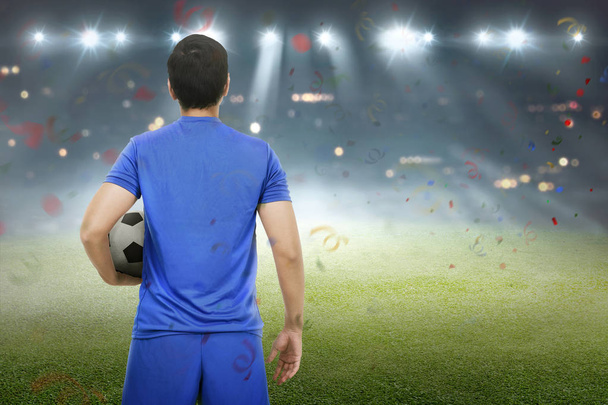 Zadní pohled na asijské fotbalista stojí s míčem na hřišti - Fotografie, Obrázek