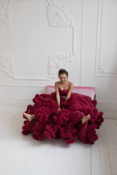 Cheerful young woman in a burgundy ball gown. - Foto, Imagem