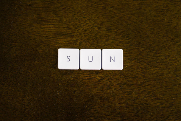 SUN word written on plastic keyboard alphabet with dark background - Foto, afbeelding