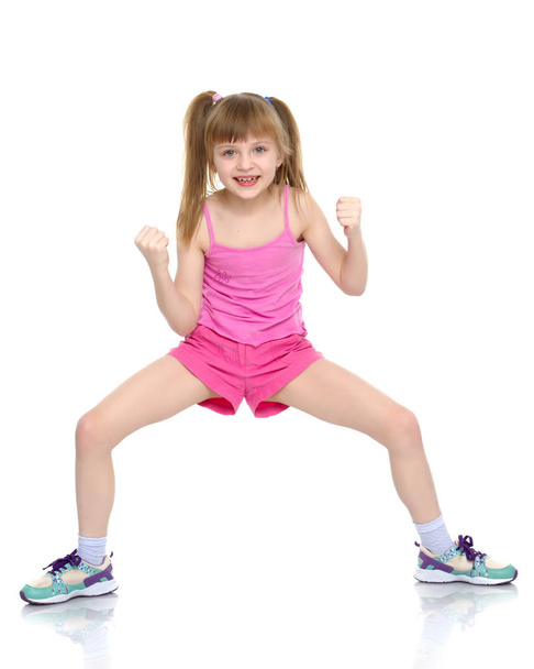 A little girl shows her muscles. - Foto, imagen