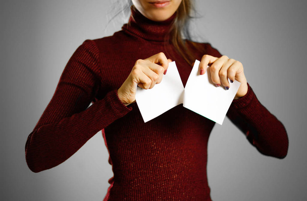 Girl tearing a piece of paper in half blank white flyer brochure booklet. Leaflet presentation - Zdjęcie, obraz