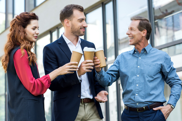 cheerful successful business team clinking with disposable cups of coffee - Photo, Image